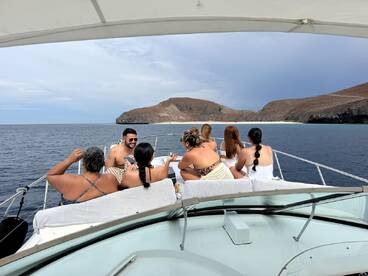 A lively group enjoys a day on the water, soaking in the sun and scenery aboard a boat, with a stunning island backdrop — perfect for celebrations and memorable outings.