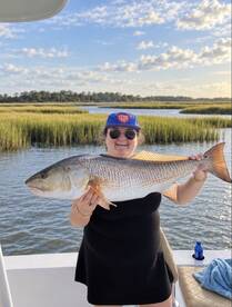 A joyful angler proudly displays her catch of the day, a large fish, while enjoying a beautiful day on the water — a perfect moment for fishing enthusiasts.