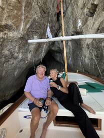 A couple enjoys drinks aboard a boat nestled in a stunning cave, capturing a moment of relaxation and adventure on the water.