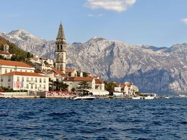 A picturesque view of a coastal town with stunning mountains in the background, showcasing the beauty of the harbor and its charming architecture.