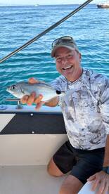 A happy angler proudly displays his catch aboard a boat, showcasing the thrill of fishing on the water.