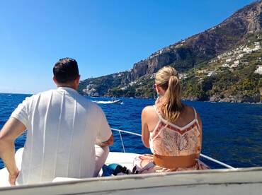 A couple enjoys a scenic boat ride along the stunning Amalfi Coast, capturing the beauty of the coastline and the joy of their experience on the water.