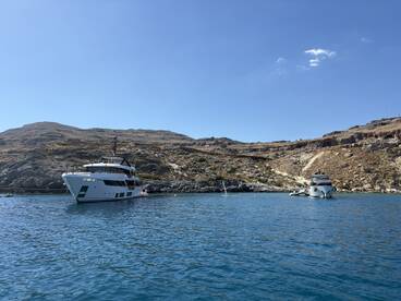 A stunning yacht anchored in calm turquoise waters, surrounded by rocky hills — an ideal setting for luxury boating adventures.