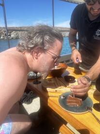 A man prepares to enjoy a delicious dessert aboard a boat, capturing a moment of celebration and enjoyment on the water.