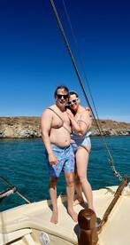 A happy couple poses together on the deck of a boat, enjoying a sunny day on the ocean — perfect for romantic getaways or fun adventures at sea.