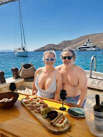 A couple enjoys a delightful spread of gourmet snacks and cocktails aboard a yacht, surrounded by stunning coastal views — perfect for romantic getaways or special celebrations.