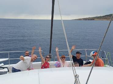 A cheerful group waves from the deck of a boat, enjoying their time on the ocean — perfect for group outings and celebrations.