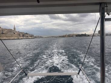 A scenic view of the coastline while underway, showcasing the historic architecture and natural beauty of the harbor.
