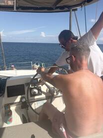 Two individuals are engaged at the helm of a boat, focusing on navigation and steering, showcasing the interior space of the vessel.