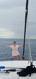 A joyful woman poses on the deck of a sailboat, embracing the ocean breeze — a perfect moment for sailing adventures and memorable experiences on the water.
