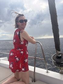 A woman enjoys the ocean breeze on a boat, showcasing a joyful moment while sailing — perfect for capturing the essence of a relaxing day on the water.