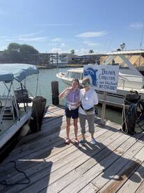A joyful moment captured at the dock with a family posing for a photo, showcasing their excitement for the Dolphin Connection experience. Perfect for family outings and marine adventures.