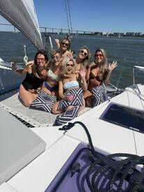 A fun group of friends enjoys a sunny day sailing on a catamaran, celebrating with smiles and laughter — perfect for a memorable outing on the water.