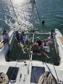 A lively group enjoys a sunny day aboard a catamaran, relaxing and celebrating together on the water — perfect for memorable outings and adventures.