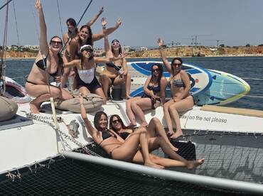 A lively group of friends celebrates aboard a catamaran, enjoying the sun and each other's company — perfect for a fun day on the water.