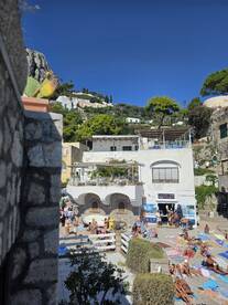 A vibrant scene at a beach in Capri, where sunbathers enjoy the warm weather and stunning views — perfect for summer getaways and relaxation.