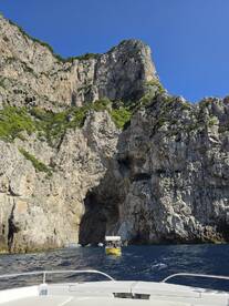 A stunning view of rocky cliffs and a cave entrance, with boats navigating the waters — an ideal setting for exploring coastal wonders.