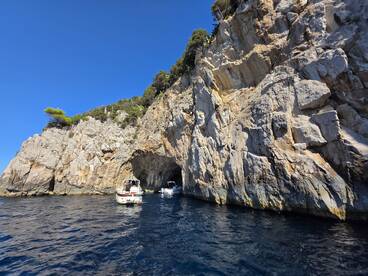 A stunning view of boats near a rocky coastline with a cave entrance, showcasing the beauty of the natural landscape — perfect for exploring hidden gems on the water.