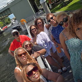 A lively group of friends poses for a selfie on the dock, ready for a fun day on the water — perfect for celebrations and outings.