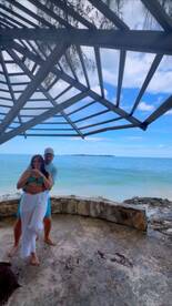 A couple enjoys a moment together by the beach, celebrating with cocktails and a stunning ocean view — perfect for romantic getaways or special occasions.