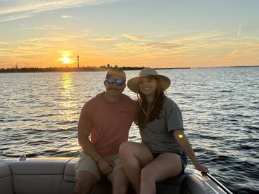 A couple enjoys a picturesque sunset on a pontoon boat, capturing a perfect moment of relaxation and celebration on the water.