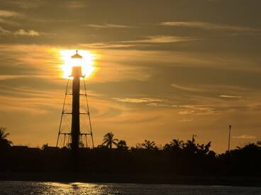 A silhouette of a lighthouse against a sunset backdrop, creating a beautiful yet unclear scene.