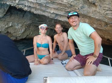 A cheerful group enjoys their time aboard a boat near a stunning cave, capturing the essence of adventure and fun on the water.