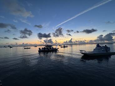 A picturesque sunset scene featuring multiple boats on calm waters, perfect for evening cruises and group outings.
