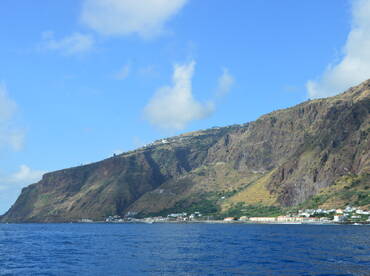 A stunning view of a rugged coastline and lush hills, showcasing the natural beauty of the island — perfect for scenic boat tours and exploration.