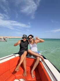 Two friends enjoy a fun moment on the bow of a boat, showcasing the joy of boating adventures together in clear waters.