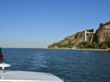 A scenic view from the bow of a boat, showcasing a rocky coastline and clear blue waters, perfect for exploring coastal destinations.