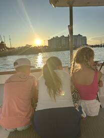 A group of children enjoys a beautiful sunset from the deck of a boat, creating a memorable moment on the water.