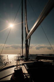A stunning view of a sailboat's mast against a shimmering sea and bright sun, capturing the essence of sailing adventures.