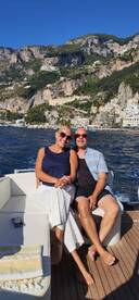 A couple enjoys a sunny day on a boat, surrounded by stunning coastal scenery — perfect for romantic getaways or scenic tours.