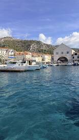 A scenic view of boats docked in a picturesque harbor, surrounded by charming buildings and lush hills, perfect for exploring coastal destinations.