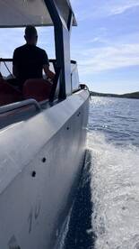A side view of a boat in motion, showcasing the sleek design and the water spray as it cuts through the waves. Perfect for highlighting the thrill of boating adventures.