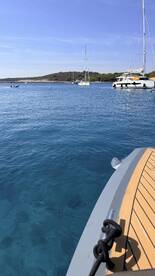 A serene view of a catamaran anchored in clear blue waters, showcasing the beautiful coastline and tranquil surroundings — perfect for a relaxing day on the water.