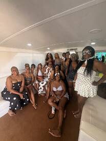 A lively group of friends poses together inside a boat, showcasing their stylish swimwear and enjoying a fun day on the water — perfect for celebrations and gatherings.