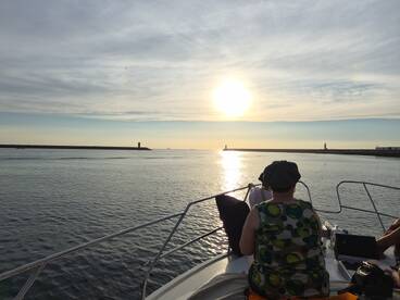 A serene sunset view from the bow of a boat, with guests enjoying the tranquil waters and picturesque scenery — perfect for evening cruises.