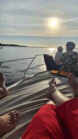 Guests relax on the deck of a boat, enjoying a beautiful sunset over the water — a perfect moment for unwinding and taking in the scenic views.