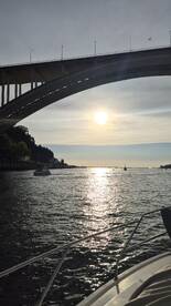 A stunning sunset view over a waterway, framed by a bridge, showcasing the serene beauty of the landscape — perfect for evening boat rides.