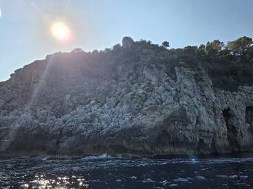 A stunning view of a rocky coastline under the bright sun, showcasing the natural beauty of the landscape — perfect for scenic boat tours.