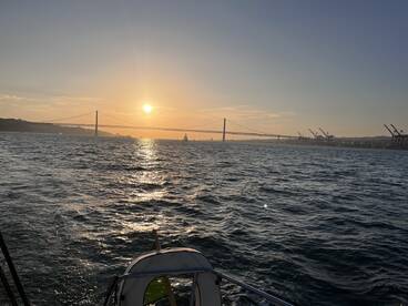 A stunning sunset view over the water with a bridge in the background, perfect for capturing the beauty of sailing experiences.