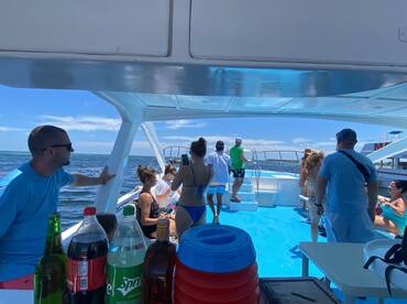 A lively group enjoys a day on the water aboard a boat, with drinks in hand and the ocean as their backdrop — perfect for a fun-filled adventure.