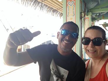 A cheerful couple poses for a selfie, enjoying their time at a vibrant waterfront location — perfect for capturing memorable moments during their boating adventure.