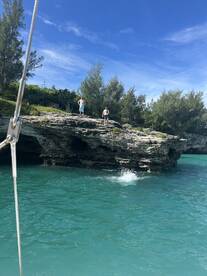 Two individuals prepare to jump into the stunning turquoise waters from a rocky outcrop, capturing the essence of adventure and fun in a beautiful outdoor setting.