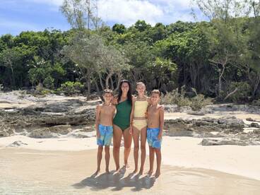 A joyful family poses together on the beach, capturing a memorable moment in a tropical paradise — perfect for family vacations and beach outings.