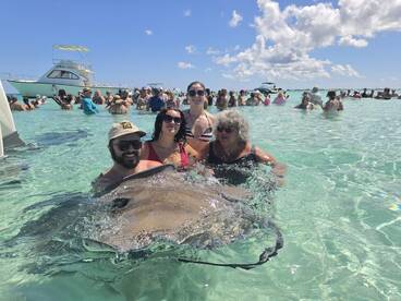 A group of friends interacts with stingrays in shallow waters, creating a memorable wildlife experience in a vibrant marine setting.
