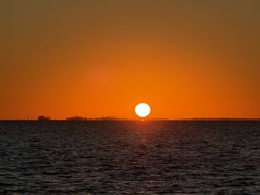 A stunning sunset over the water, creating a picturesque backdrop perfect for evening boat cruises.