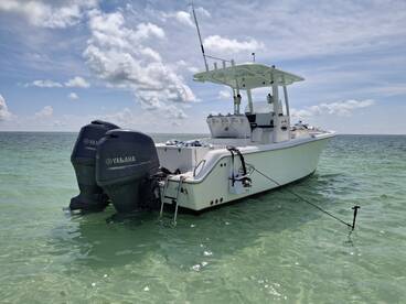 A sleek center console boat anchored in crystal-clear waters, showcasing its powerful Yamaha engines — perfect for fishing or leisurely outings.
